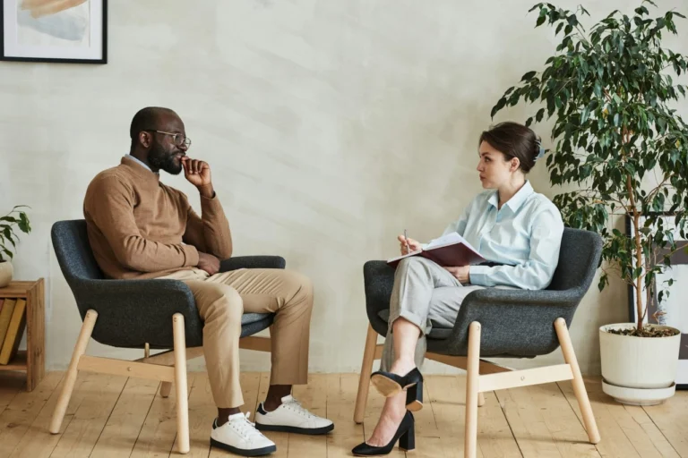 Psychologist taking notes during an individual therapy session with a man